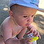 baby, bracelet, cap, child, closeup, curious, daylight, giraffe, hand, infant, outdoor, park, person, play, shadow, skin, squatting, sunlight, toy, young_child