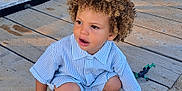 Jaron a rejoint le concours — aidez-le/la à gagner de superbes lots ! toddler, child, curly_hair, striped_shirt, sneakers, toy, playing, outdoor, dock, wooden_planks, sand, sunlight, casual_clothing, cute, person, young_child, crouching, daylight, fun, curiosity