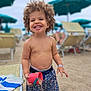 Jaron participe au concours pour gagner de l'argent avec cette photo : toddler, child, smiling, beach, sand, bucket, curly_hair, shorts, umbrella, sunny, outdoor, play, happy, summer, vacation, sandals, sand_pouring, bare_chested, fun, daytime