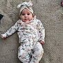 baby, carpet, casual, child, comfort, cute, floor, floral_clothing, headwrap, indoor, infant, lying_down, one_piece_outfit, patterned_clothing, person, portrait, small_feet, small_hand, soft_lighting, young_child