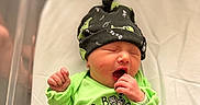 Kiara joined the competition — help win amazing prizes! newborn, baby, crib, hospital, yawning, infant, hat, green_clothing, black_clothing, blanket, bed, sleeping, cute, app_icons, phone_screen, monitor, camera_feed, indoors, person, resting