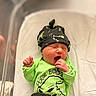 newborn, baby, crib, hospital, yawning, infant, hat, green_clothing, black_clothing, blanket, bed, sleeping, cute, app_icons, phone_screen, monitor, camera_feed, indoors, person, resting