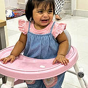 Enayah joined the competition — help win amazing prizes! adult_leg, baby, child, crying, denim_overall, emotion, expression, footwear, furniture, hair_accessory, hands, home_interior, indoor, pigtails, pink_shirt, pink_walker, portrait, tile_floor, toddler, toy