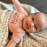 Scarlettt is registered to the contest to win money with this photo: arms, baby, blanket, child, clothing, cozy, cute, expression, face, floral_pattern, happy, indoor, infant, lying_down, newborn, person, pink_clothing, portrait, smiling, soft_focus