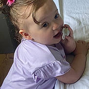 Gracie-Maè joined the competition — help win amazing prizes! toddler, child, pacifier, purple_shirt, hair_ties, pink_flowers, bed, white_bed_sheet, curly_hair, indoor, wooden_floor, cute, baby, person, smiling, young_child, playful, hand, face, clothing