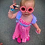 Gracie-Maè joined the competition — help win amazing prizes! child, toddler, sunglasses, pink_dress, toy, pacifier, footwear, pavement, outdoor, person, summer, cute, accessory, fashion, playful, standing, hand, hair, face, sunny