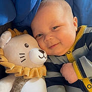 Kyaire joined the competition — help win amazing prizes! baby, child, plush_toy, lion, smile, striped_clothing, onesie, yellow_trim, blue_background, snuggle, soft_toy, cute, infant, face, happy, cozy, portrait, indoor, person, close_up