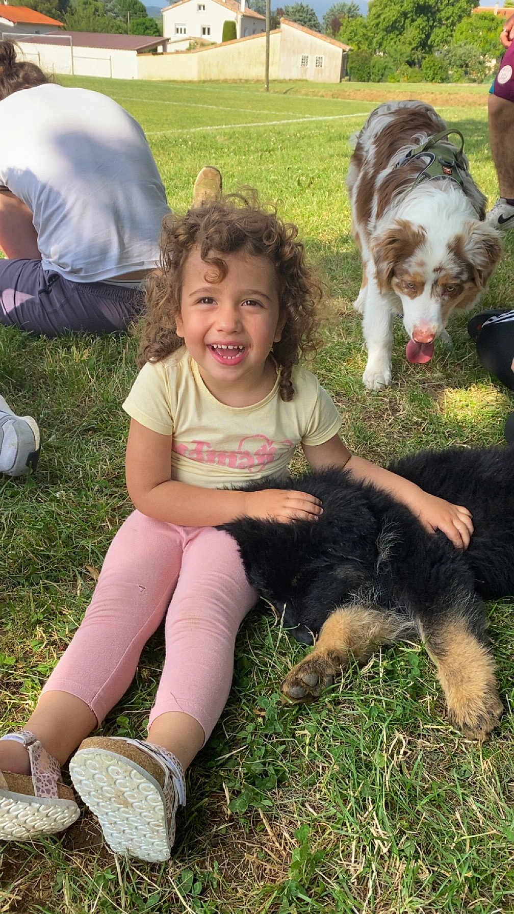 Maddy a rejoint le concours — aidez-le/la à gagner de superbes lots ! child, curly_hair, smiling, sitting, grass, puppy, dog, pet, outdoor, sunny, field, people, casual_clothing, pink_pants, yellow_shirt, footwear, happy, playful, animal, nature