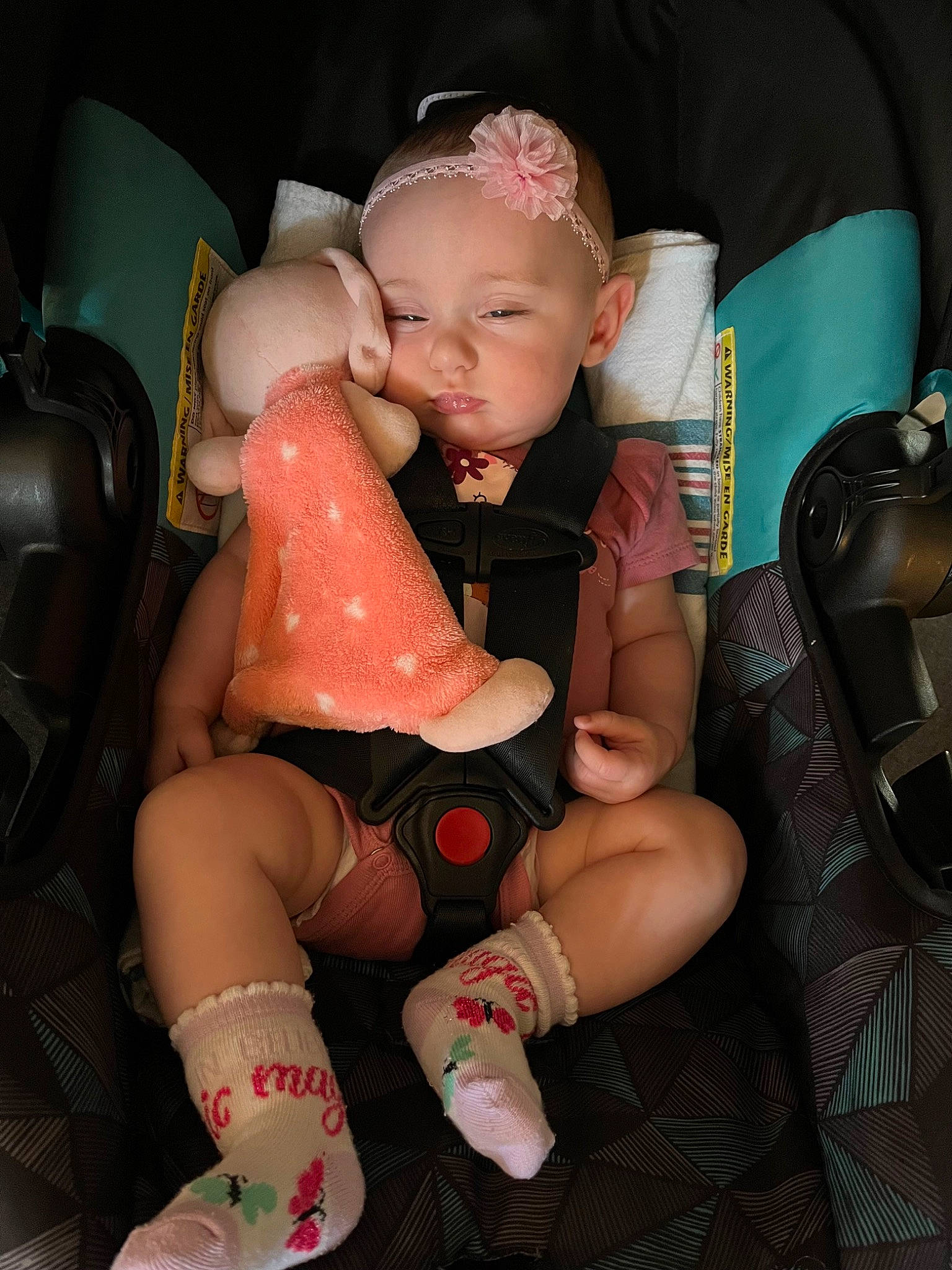 Annabelle is registered to the contest to win money with this photo: baby, baby_toddler_clothing, car_seat, child, comfort, finger, human_leg, joint, knee, lap, leg, mouth, nail, person, pink, shoe, sitting, skin, sock, thigh