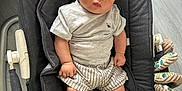 Mahé a rejoint le concours — aidez-le/la à gagner de superbes lots ! baby, baby_rocker, casual, child, clothing, expression, face, floor, footwear, gray_tshirt, hands, home_interior, infant, legs, seated, sneakers, soft_toys, striped_shorts, toddler, toy