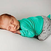 Barrett is registered to the contest to win money with this photo: baby, sleeping, infant, child, cute, turquoise_clothing, gray_pants, spikes, soft_surface, white_background, peaceful, portrait, resting, young_child, newborn, cozy, comfort, face, hand, closed_eyes