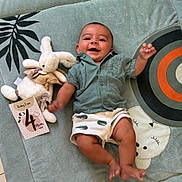 Liam participe au concours pour gagner de l'argent avec cette photo : animal_face, baby, bunny, celebration, child, cute, floor, four_months, green_shirt, happy, indoor, infant, lying_down, milestone_card, pattern, play_mat, plush_toy, shorts, smiling, toy