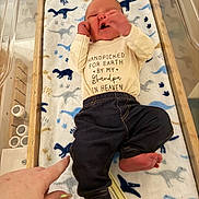Killian joined the competition — help win amazing prizes! baby, baby_boy, blanket, clothing, crib, cute, dinosaur_pattern, fingernails, foot, hand, indoor, infant, lying_down, newborn, pants, person, shirt, soft_texture, toddler, wooden_crib