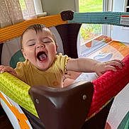 Zoey joined the competition — help win amazing prizes! baby, child, playpen, yellow_clothing, happy, smiling, indoor, home, window, curtains, colorful, toy_area, toddler, cute, grip, face, mouth_open, joyful, person, playtime