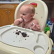 James joined the competition — help win amazing prizes! baby, high_chair, cake, messy, kitchen, face, hands, food, child, curious, sitting, plate, crumbs, cabinet, window, dish, water_bottle, floor, indoors, person