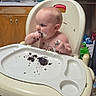 baby, high_chair, cake, messy, kitchen, face, hands, food, child, curious, sitting, plate, crumbs, cabinet, window, dish, water_bottle, floor, indoors, person