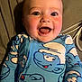 Sawyer joined the competition — help win amazing prizes! baby, smiling, onesie, blue_clothing, cartoon_print, face, happy, infant, child, cute, lying_down, indoors, closeup, person, cable, background, skin, head, eyes, mouth
