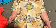 Sawyer is registered to the contest to win money with this photo: baby, child, dinosaur_shirt, shorts, bed, towel, turtle_pattern, clothing, infant, person, cute, portrait, indoor, lying_down, curious, casual, colorful, young_child, fabric, comfortable