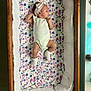 Taylor is registered to the contest to win money with this photo: baby, crib, floral, headband, socks, infant, wooden_crib, blanket, sleeping_area, cute, child, apparel, pattern, fabric, baby_clothes, resting, indoors, soft, newborn, portrait
