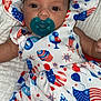baby, infant, pacifier, hat, dress, red_white_blue, stars, stripes, cupcake_pattern, balloons, american_flag, blanket, face, person, portrait, lying_down, cute, child, clothing, celebration