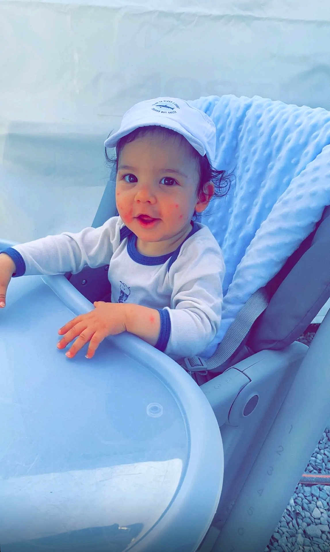 York participe au concours pour gagner de l'argent avec cette photo : baby, blue, cap, child, clothing, curly_hair, cute, expression, face, hand, high_chair, indoor, infant, person, seat, skin, soft_texture, table, toddler, young