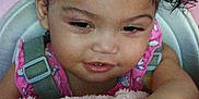 Layla is registered to the contest to win money with this photo: baby, blanket, child, closeup, clothing, cushion, cute, expression, face, hair, hand, indoors, person, pigtails, pink, seat, skin, smile, toddler, young_child