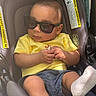 baby, child, car_seat, sunglasses, yellow_shirt, blue_shorts, sock, infant, cool, fashion, portrait, cute, seatbelt, hands, legs, indoor, casual, relaxed, young, person