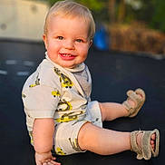 Carter joined the competition — help win amazing prizes! baby, child, smiling, outdoor, trampoline, sandals, happy, cute, blond_hair, shorts, tshirt, sunlight, nature, grass, playing, summer, portrait, sitting, young, fun