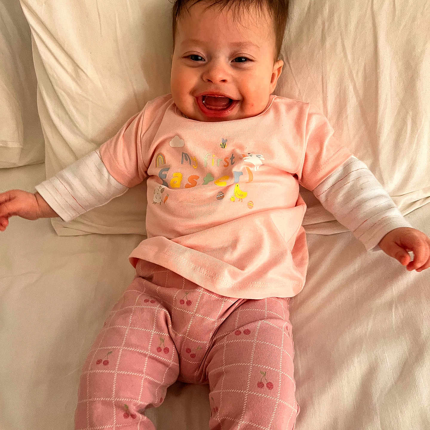 Daisy joined the competition — help win amazing prizes! baby, bed, celebration, cherry_pattern, child, cute, easter, happy, indoors, infant, long_sleeves, lying_down, patterned_pants, person, pink_clothing, portrait, smiling, toddler, white_bed_sheet, young_child