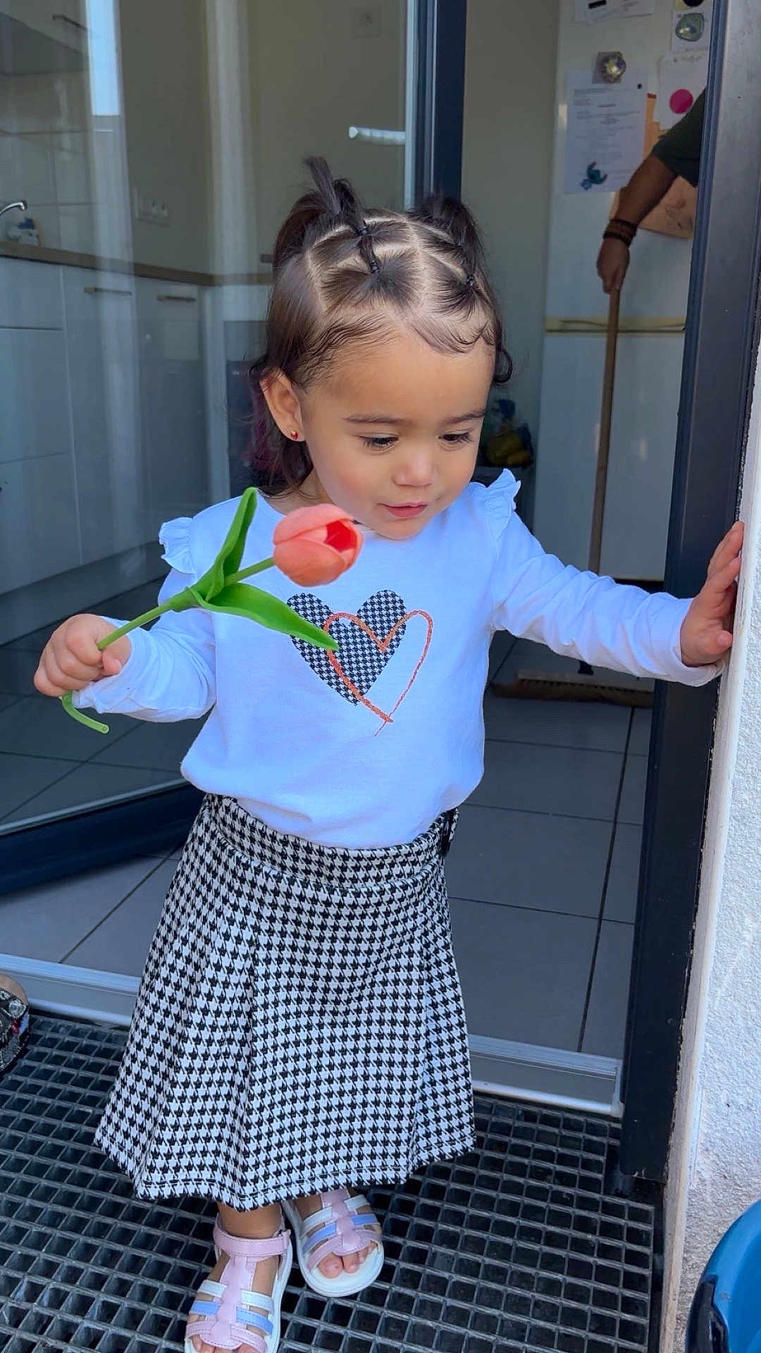Harmonie participe au concours pour gagner de l'argent avec cette photo : toddler, child, flower, tulip, doorway, kitchen, hair_style, skirt, shirt, footwear, sandals, floor, tile, hand, person, indoors, window, light, home, cute