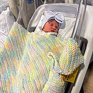 Oaklyn joined the competition — help win amazing prizes! newborn, baby, hospital, bassinet, blanket, knitted_blanket, sleeping, hat, bow, infant, bed, person, healthcare, cute, rest, indoor, soft, peaceful, wrapped, cozy