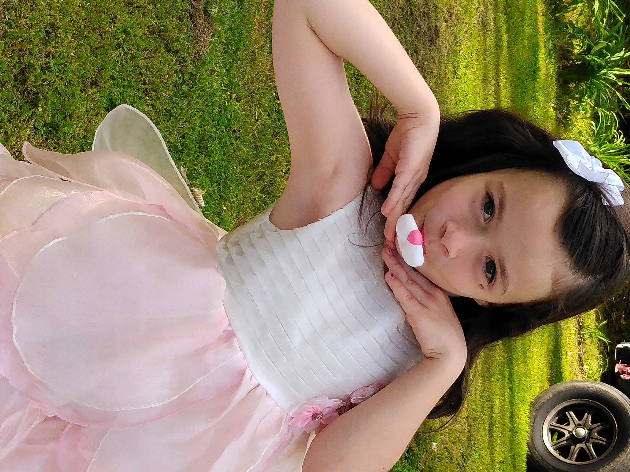 Rayne is registered to the contest to win money with this photo: arm, automotive_tire, black_hair, dress, flash_photography, gesture, grass, green, hand, happy, human_body, light, meadow, people_in_nature, person, plant, skin, thigh, tire, tree