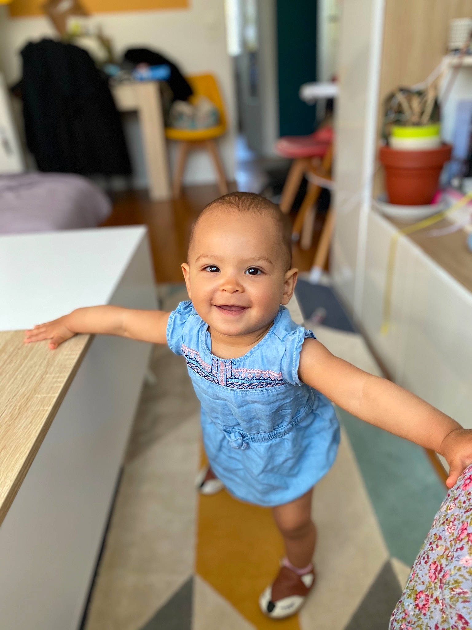 Anaïs a rejoint le concours — aidez-le/la à gagner de superbes lots ! baby, baby_toddler_clothing, chair, child, desk, floor, flooring, fun, happy, hardwood, joy, leisure, person, shorts, sitting, smile, standing, t_shirt, table, toddler