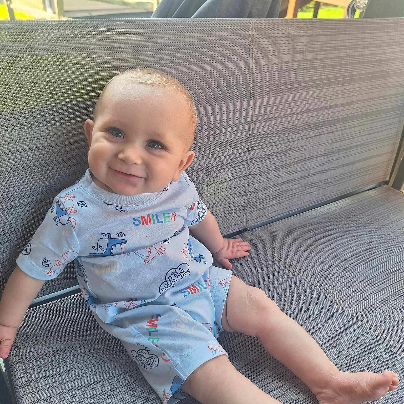 Hunter is registered to the contest to win money with this photo: baby, barefoot, bench, casual, child, clothing, cute, cute_baby, dinosaur_print, happy, infant, joyful, outdoor, playful, portrait, sitting, smiling, summer, sunlight, young_child