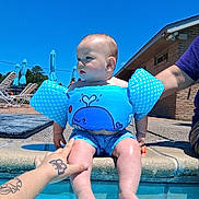 Bowen joined the competition — help win amazing prizes! baby, child, swimming_pool, floaties, water, summer, sunny, blue_sky, tattoo, adult_hand, swimwear, outdoor, poolside, legs, sitting, person, building, umbrella, relaxation, daytime