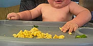 Bowen joined the competition — help win amazing prizes! baby, high_chair, macaroni, food, messy, smiling, child, indoor, face, hand, foot, tray, seat, furniture, blue_wall, decor, person, cute, feeding, home