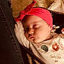 baby, sleeping, headband, pink, onesie, embroidery, blanket, cozy, cute, infant, child, soft_lighting, face, peaceful, resting, clothing, closeup, indoor, warm_tones, portrait