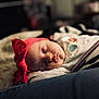 baby, sleeping, headband, red, blanket, cozy, infant, soft_lighting, closeup, face, peaceful, indoors, cute, child, resting, portrait, warm_tones, toddler, clothing, bed