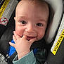 adorable, baby, car_seat, child, closeup, clothing, cute, eyes, face, hand, happy, indoor, infant, person, portrait, safety, seatbelt, smiling, warning_label, young_child
