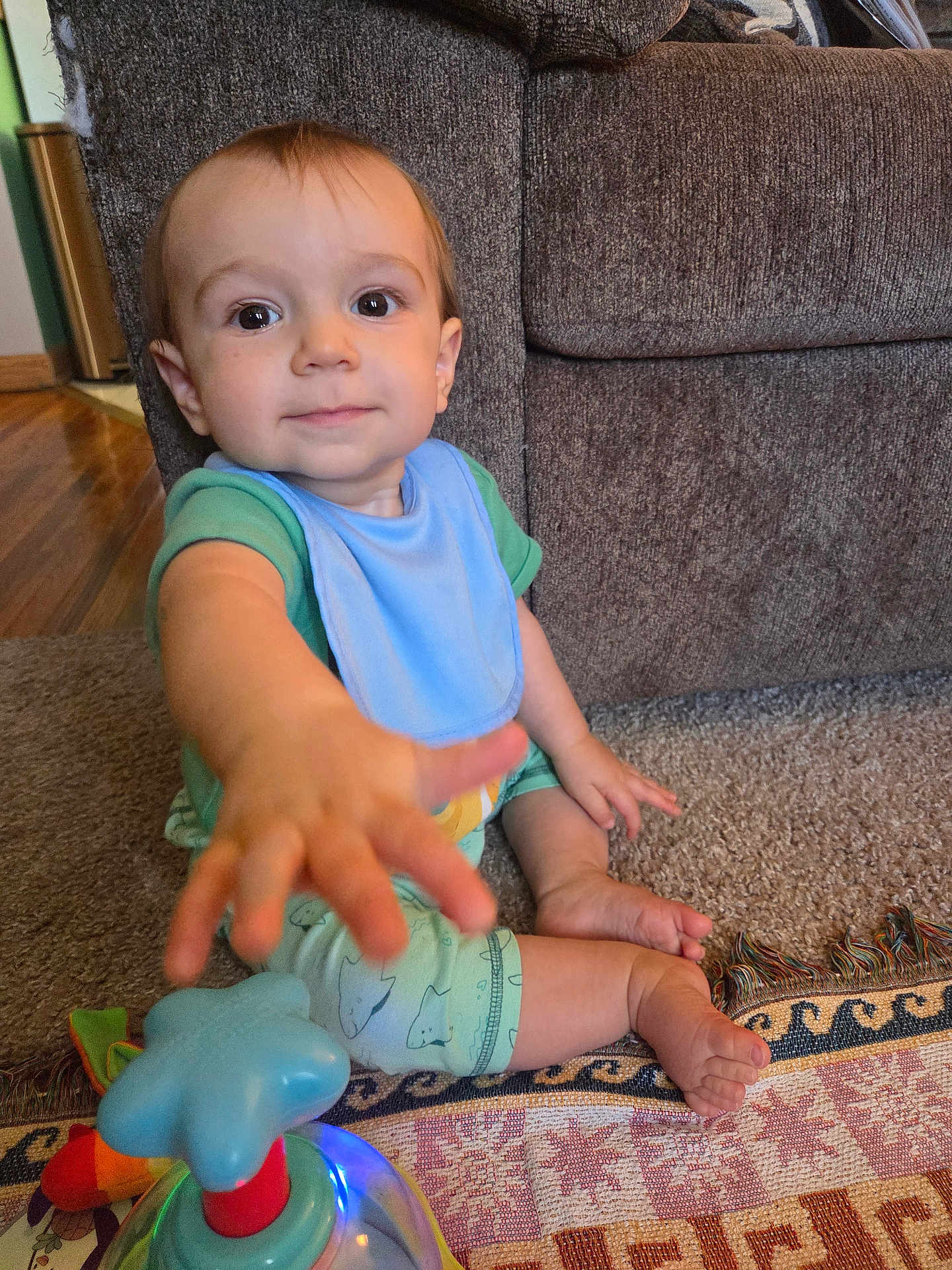 Jackson joined the competition — help win amazing prizes! baby, toddler, child, blue_bib, toy, carpet, couch, indoor, hand, foot, curious, sitting, clothing, colorful_toy, light, home, floor, young_child, person, playtime
