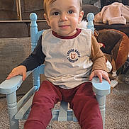 Jackson is registered to the contest to win money with this photo: toddler, child, blue_chair, sitting, indoor, carpet, toy, furniture, smiling, long_sleeve_shirt, pants, cozy, home, face, person, cute, happy, young_child, wooden_chair, casual_clothing