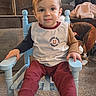 toddler, child, blue_chair, sitting, indoor, carpet, toy, furniture, smiling, long_sleeve_shirt, pants, cozy, home, face, person, cute, happy, young_child, wooden_chair, casual_clothing