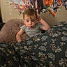 toddler, child, blanket, pillow, striped_shirt, indoor, wall_mural, giraffe, elephant, tiger, zebra, animal_art, curious, bedroom, floral_pattern, cute, portrait, young_child, cozy, playful