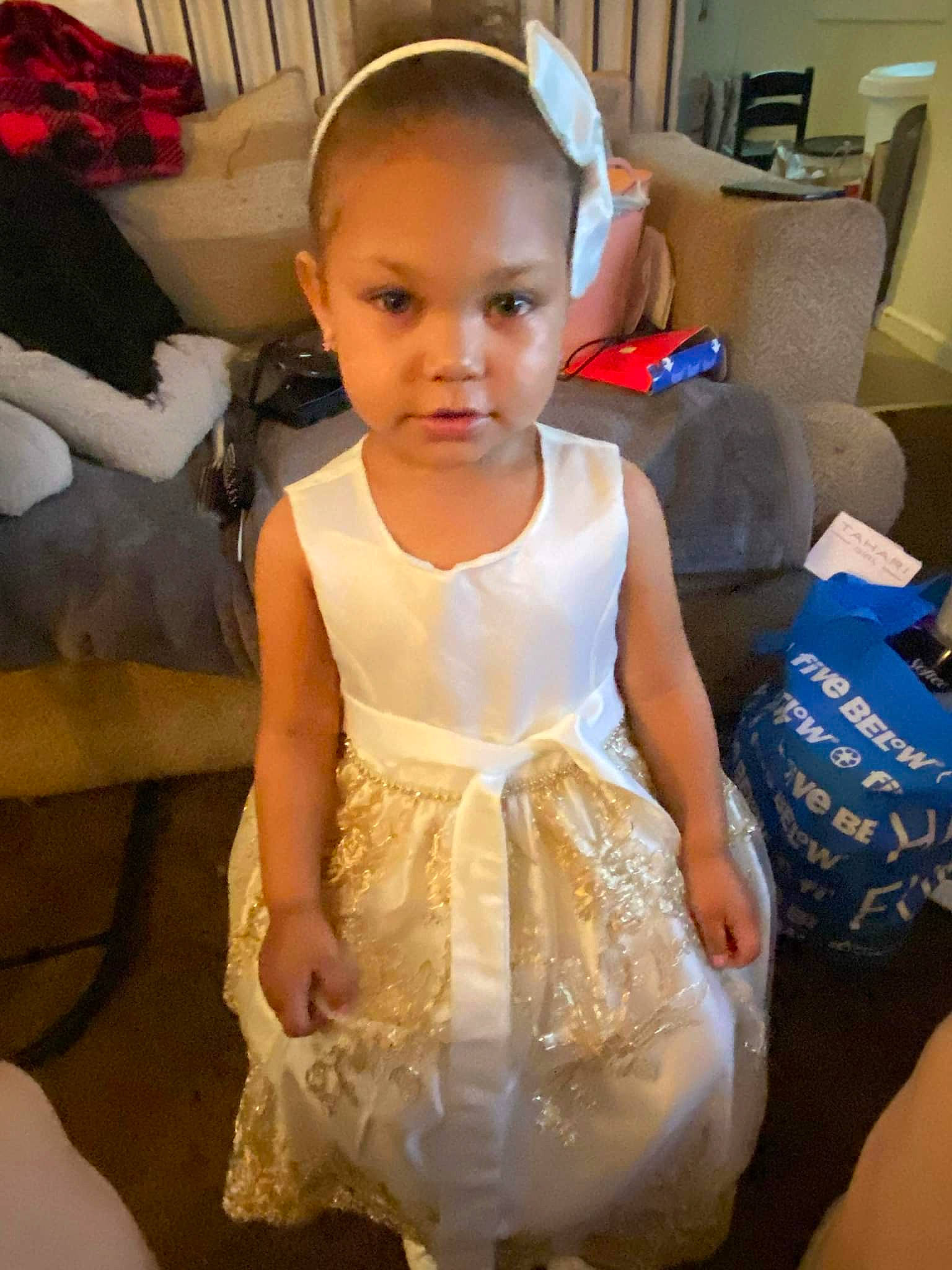 Kamorah is registered to the contest to win money with this photo: baby_toddler_clothing, chair, child, dress, embellishment, event, face, fashion_design, flooring, formal_wear, fun, happy, iris, person, room, ruffle, shipping_box, sitting, t_shirt, toddler