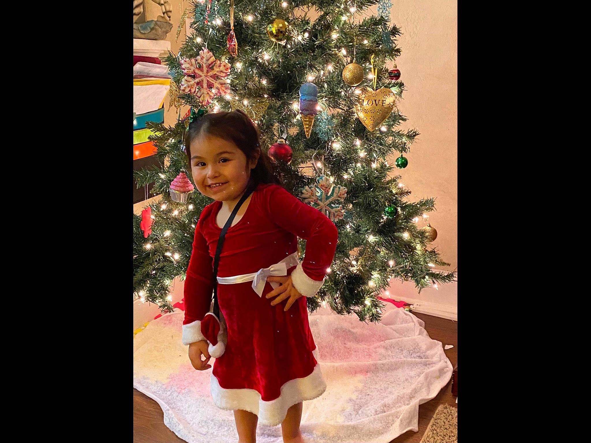 Aaliyah is registered to the contest to win money with this photo: christmas_decoration, christmas_eve, christmas_ornament, christmas_tree, conifer, dress, event, happy, holiday, holiday_ornament, joy, long_hair, magenta, ornament, person, plant, room, sleeve, smile, toddler