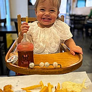 Lindsay a rejoint le concours — aidez-le/la à gagner de superbes lots ! baby_food, child, cute, face, food, french_fries, happy, high_chair, indoor, meal, nuggets, person, playful, restaurant, sippy_cup, smiling, table, toddler, white_clothing, wooden_furniture