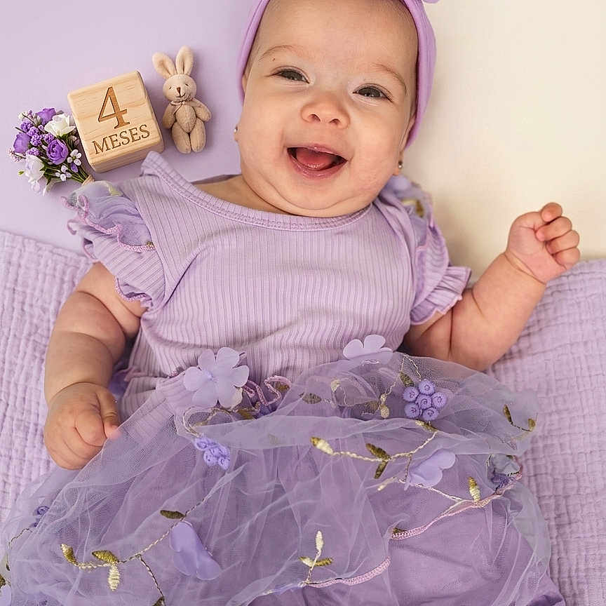 Kelly joined the competition — help win amazing prizes! accessory, baby, blanket, child, close_up, cute, dress, floral_embroidery, flowers, happy, headband, infant, lying_down, milestone_block, portrait, purple, smiling, stuffed_bunny, tutu, wooden_block