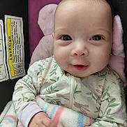 Kelly is registered to the contest to win money with this photo: baby, infant, newborn, smile, eyes, face, blanket, onesie, floral_print, car_seat, head_support, hands, cozy, closeup, portrait, cute, adorable, soft_texture, warning_label, rosy_cheeks