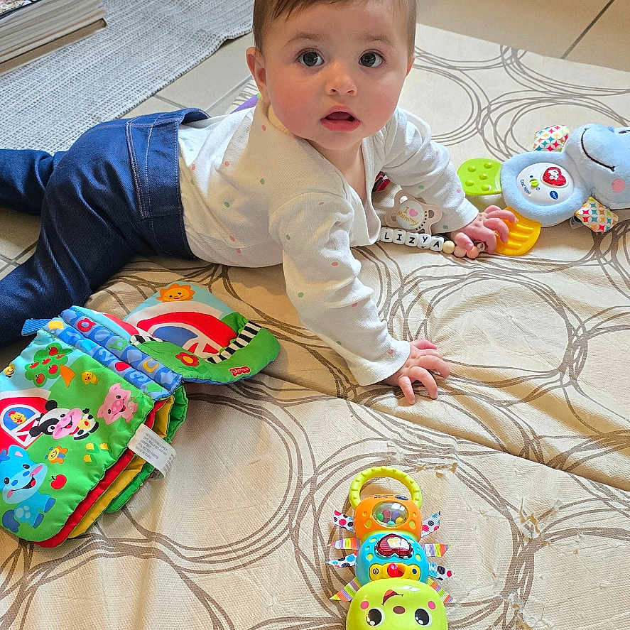 Alizya a rejoint le concours — aidez-le/la à gagner de superbes lots ! baby, book, child, clothing, colorful, container, curious, expression, face, floor, furniture, hand, head, indoor, infant, looking, mat, person, playtime, toy