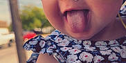 Georgia Ann is registered to the contest to win money with this photo: baby, child, face, tongue, headwrap, floral_pattern, medical_tape, dress, arm, outdoor, daylight, person, holding, smiling, cute, skin, closeup, portrait, happy, playful